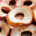 How to make dried apples (apple chips)

Ingredients and equipment
- Apples: choose crisp, firm varieties (Braeburn, Pink Lady, Cox, Granny Smith, Honeycrisp).
- Lemon juice or ascorbic acid (optional) to prevent browning.
- Sharp knife or mandoline, apple corer (optional).
- Dehydrator, oven, or air fryer; baking trays and cooling racks.

Preparation
1. Wash apples. Core apples if you prefer rings without seeds; peeling optional.
2. Slice apples uniformly, 2–5 mm thick for crisp chips, 5–8 mm for chewier slices. Use a mandoline for even thickness.
3. Prevent browning (optional): dip slices 2–5 minutes in a solution of 1 tablespoon lemon juice to 500 ml water or in a solution of vitamin C powder (ascorbic acid) per package instructions. Drain and pat slices dry.
4. Optional seasoning: sprinkle with ground cinnamon or a light dusting of sugar before drying.

Drying methods
- Dehydrator: arrange slices in a single layer, no overlap. Set at 55–63°C and dry 6–12 hours depending on thickness and variety. Check after 4–6 hours and rotate trays for even drying.
- Oven: place slices on baking trays or on racks to allow air circulation. Set oven to lowest possible temperature (ideally 80–100°C). Leave oven door slightly ajar to let moisture escape. Dry 2–4 hours for thin slices, longer for thicker slices. Turn slices halfway through.
- Air fryer: arrange in single layer, set to around 100–120°C and dry 20–60 minutes, checking and turning frequently to avoid burning.
- Sun-drying (UK climate not ideal): requires hot, dry, insect-proof conditions and several days; not recommended unless climate allows.

How to tell when ready
- Apple chips should be dry and flexible or crisp depending on target texture. They will crisp more as they cool. No visible wet spots or tackiness.
- For long-term storage aim for fully crisp slices.

Conditioning and storage
- Cool completely. Condition by placing cooled chips in a loosely sealed jar for 7–10 days, shaking daily to distribute any remaining moisture. If condensation appears, return to dehydrator/oven for further drying.
- Store in airtight containers in a cool, dark place. Well-dried apple chips keep several months; refrigeration or freezing extends shelf life.

Safety and tips
- Slice thickness and variety affect drying time and final texture.
- Avoid overcrowding trays to ensure even drying.
- Discard any slices showing mould or unpleasant odour.
- For flavoured chips, add spices before drying or toss dried chips with a little honey when warm for glazed finish.

Enjoy apple chips as a healthy snack, in muesli, or as a garnish for salads and desserts.
